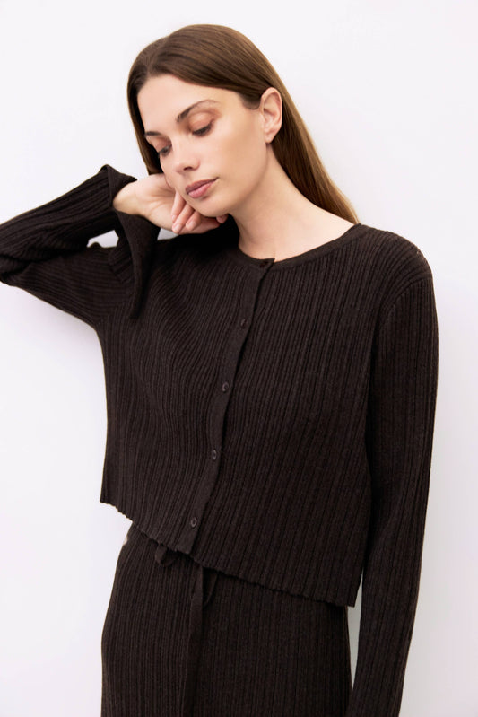 Woman wearing a black ribbed cardigan against a white background